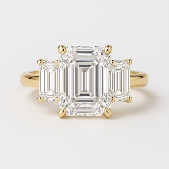 Gold ring with emerald-cut diamonds on a light gray background