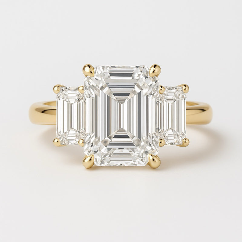 Gold ring with emerald-cut diamonds on a light gray background